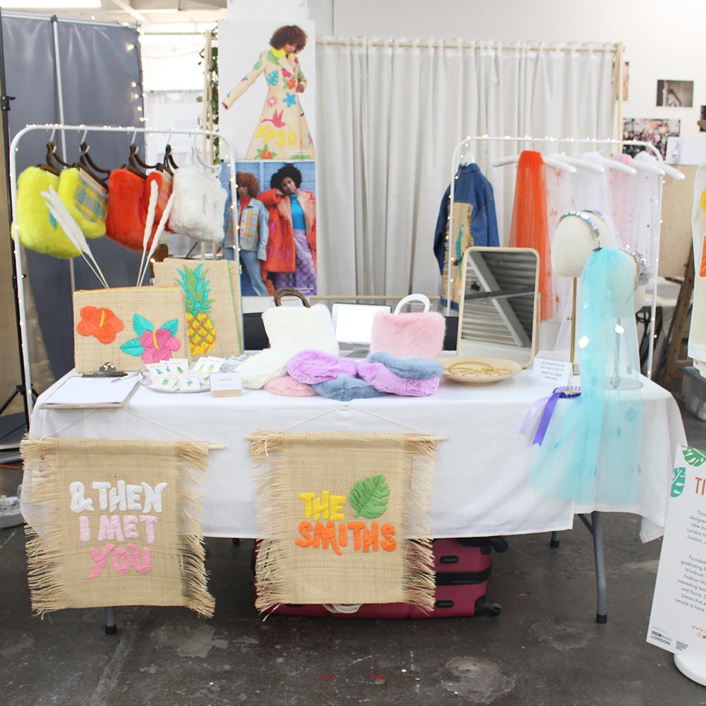 Most Curious Wedding Fair 2020 table display with the Tihara Smith bridal collection, including raffia wall hangings, raffia bags, a raffia and denim bridal jacket, wedding veils and faux fur bags