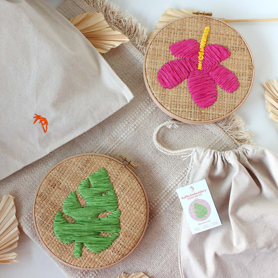 Image of two raffia embroidery hoops on a table with drawstring bags