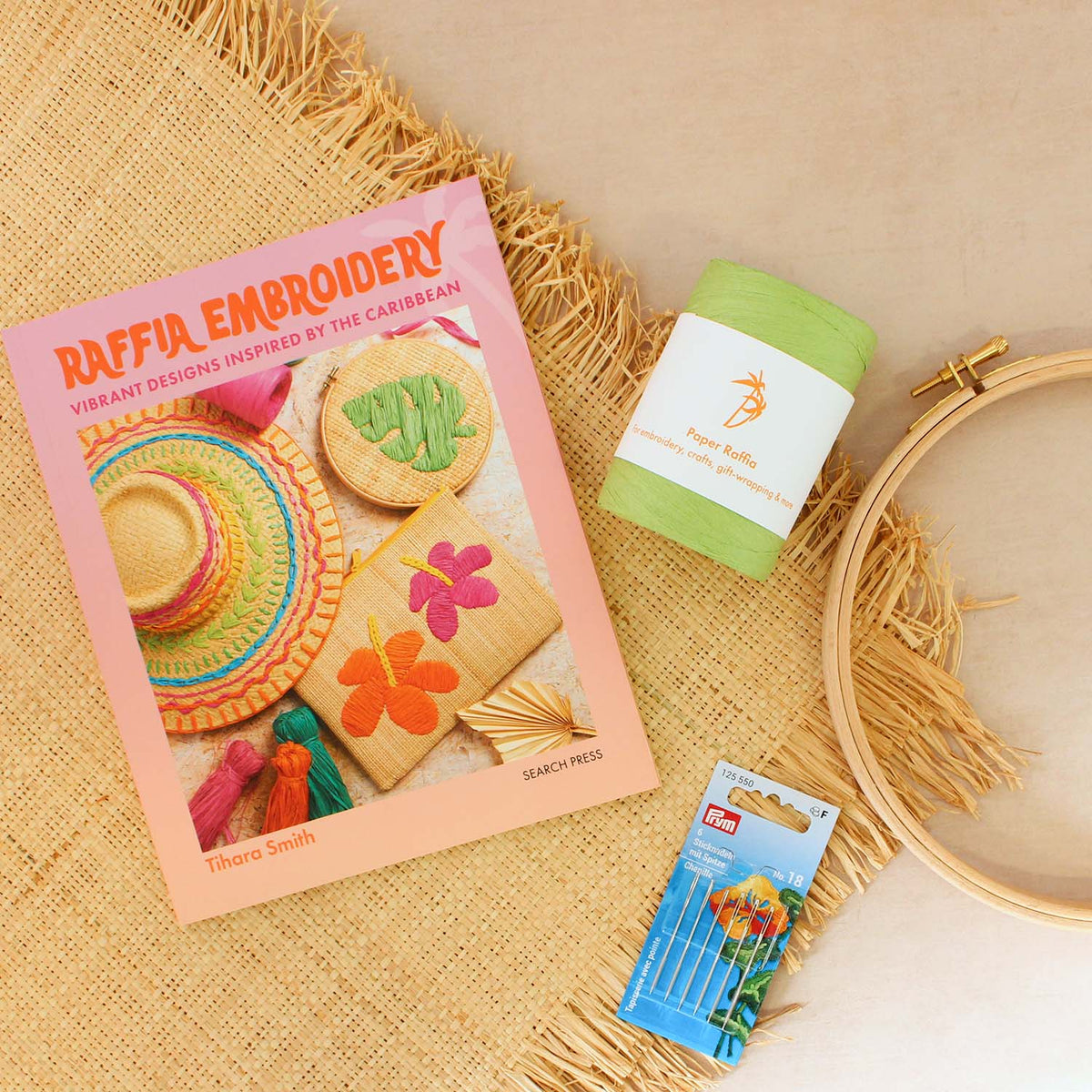 Image of raffia fabric, green raffia yarn, a quilting hoop, chenille needles and the raffia embroidery book by Tihara Smith on a beige background.