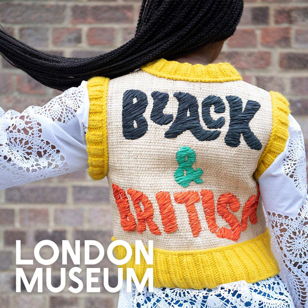 Person wearing a vest with 'Black & British' text embroidered in raffia, standing against a brick wall with 'London Museum' logo in the corner of the image.